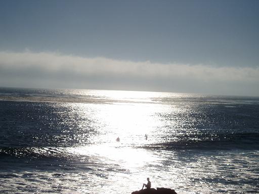 Ocean at sunset with large rock in foreground